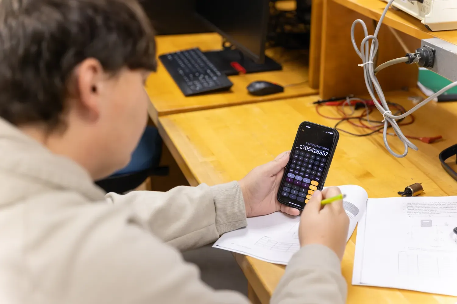 student holding a calculator at a desk