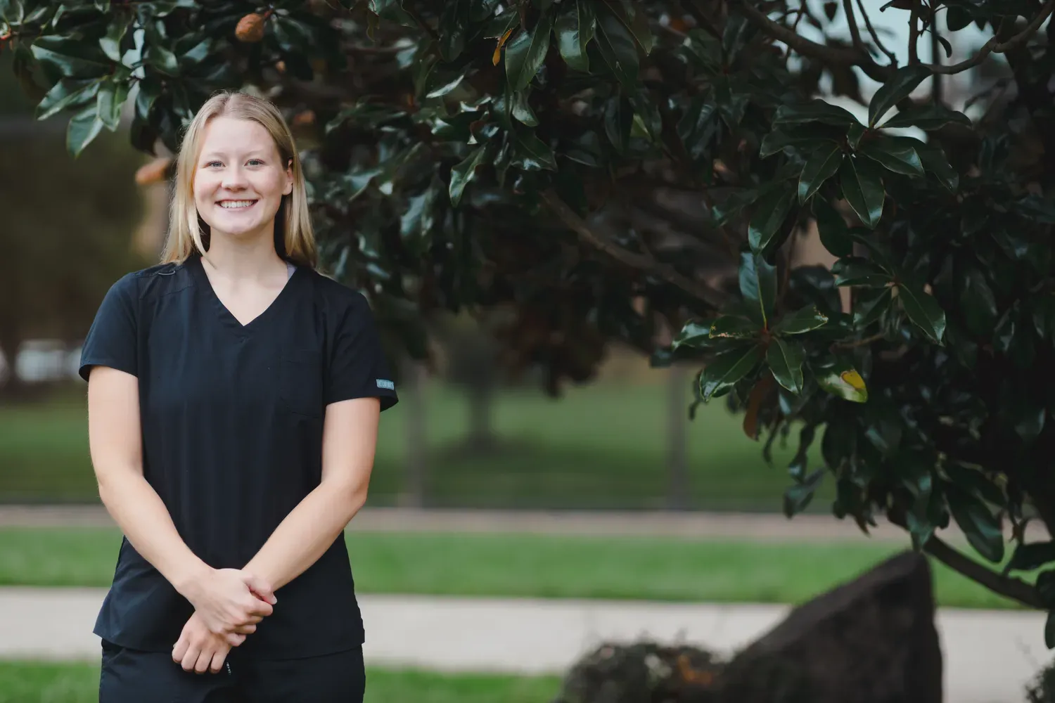 Student in scrubs smiling outside